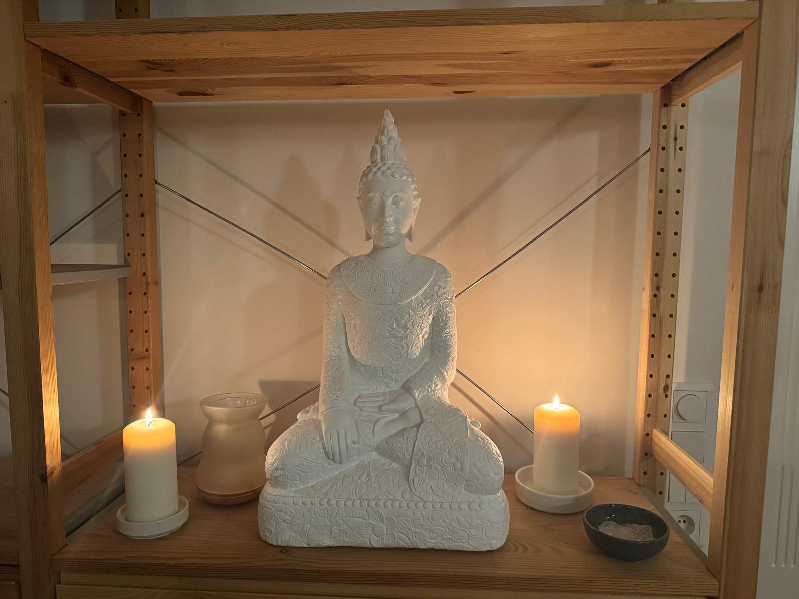 Buddha-Figur mit Kerzen in der Praxis Herz & Hände
